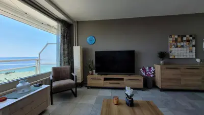 a living room with a flat screen tv and a large window at Aladdin's Sky in Zandvoort