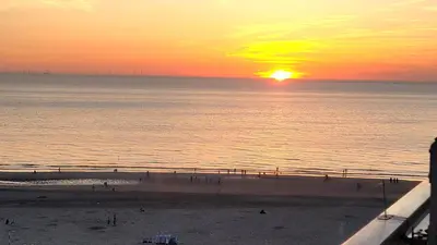 a sunset on the beach with people walking on the beach at Aladdin's Sky in Zandvoort