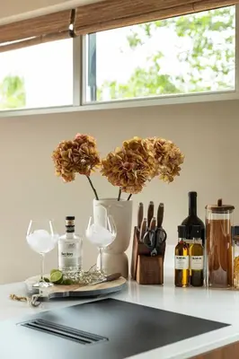a counter with wine glasses and a vase with flowers at Guesthouse De Waterliefde Loosdrecht in Breukelen