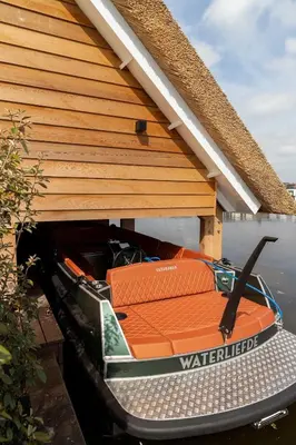 a boat sitting under a house on the water at Guesthouse De Waterliefde Loosdrecht in Breukelen