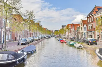a canal in a city with parked cars and boats at Studio la Riet in Alkmaar