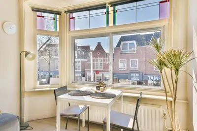 a dining room with a table and chairs in front of a window at Studio la Riet in Alkmaar