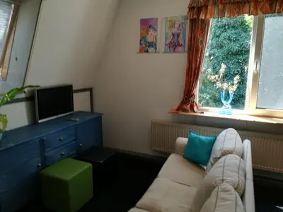 a living room with a couch and a tv at Appartement De Molshoop in Landsmeer