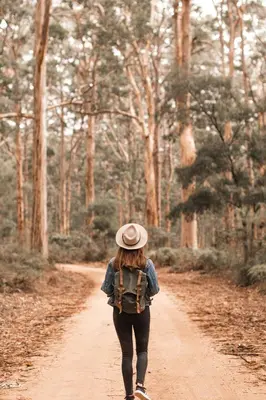 a woman walking down a dirt road with a backpack at Zoomers aan het Bos in Castricum
