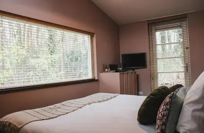a bedroom with a bed and two large windows at Zoomers aan het Bos in Castricum