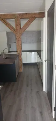 a kitchen with wooden beams in a room with wooden floors at Golf course around the corner! in Nieuwveen