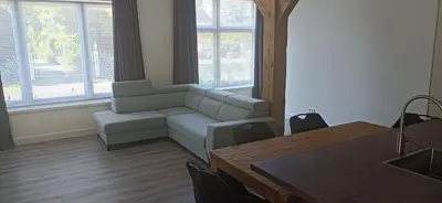 a living room with a couch and a table at Golf course around the corner! in Nieuwveen