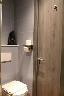 a bathroom with a toilet and a wooden door at Nebula Hotel by Ine's in Assendelft