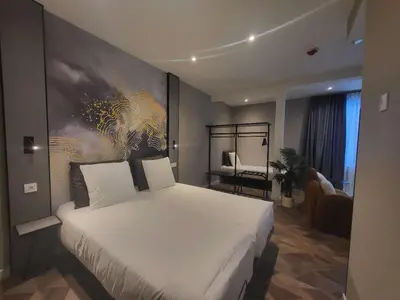 a bedroom with a large white bed with a painting on the wall at Nebula Hotel by Ine's in Assendelft