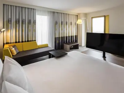 a living room with a couch and a flat screen tv at Novotel Amsterdam Schiphol Airport in Hoofddorp