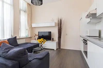 a living room with a blue couch and a tv at Authentic townhouse Alkmaar in Alkmaar