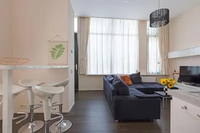a living room with a blue couch and a kitchen at Authentic townhouse Alkmaar in Alkmaar