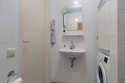 a white bathroom with a sink and a washing machine at Authentic townhouse Alkmaar in Alkmaar