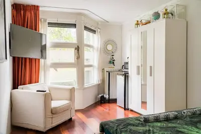 a bedroom with a bed and a chair and a television at B Center charming room on the canal in Amsterdam