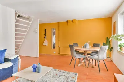 a dining room with a table and chairs and a yellow wall at De Laat Vintage in Alkmaar