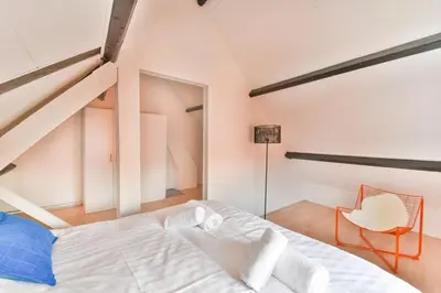 a bedroom with a white bed and a chair at De Laat Vintage in Alkmaar