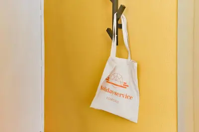 a white bag is hanging on a yellow wall at De Laat Vintage in Alkmaar