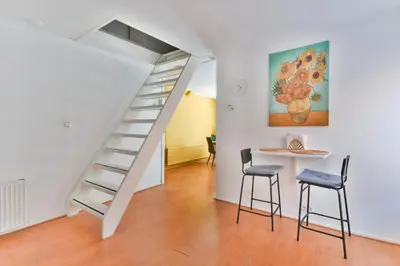 a white staircase in a room with a table and stools at De Laat Vintage in Alkmaar