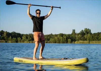 a man standing on a paddle board in the water at Luxe Glamping tent met sterrenhemel in Rijsenhout