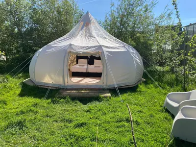 a tent with a bed in a field of grass at Luxe Glamping tent met sterrenhemel in Rijsenhout