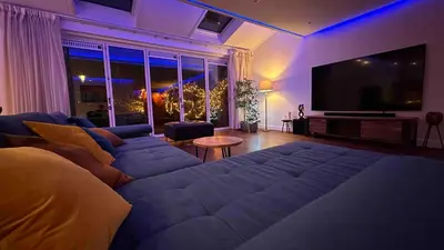 a living room with a couch and a flat screen tv at Modern and luxury vacation house, private Jacuzzi in Zoetermeer