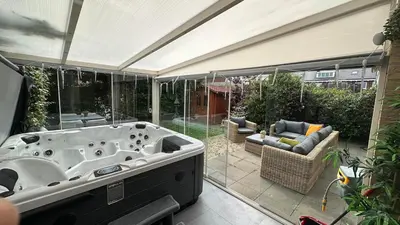 a bath tub in a room with glass walls at Modern and luxury vacation house, private Jacuzzi in Zoetermeer