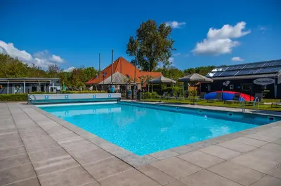 a swimming pool with blue water in front of a building at EuroParcs Buitenhuizen in Velsen-Zuid