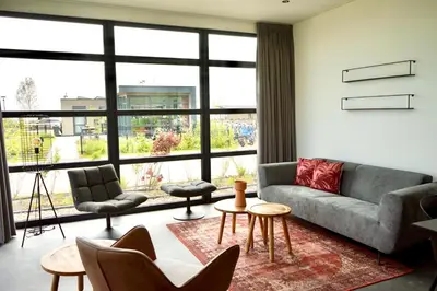 a living room with a couch and chairs and a large window at EuroParcs Buitenhuizen in Velsen-Zuid