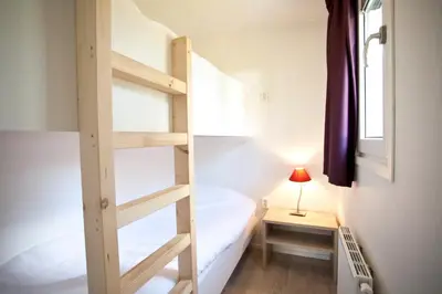 a small room with a bunk bed and a lamp at EuroParcs Buitenhuizen in Velsen-Zuid
