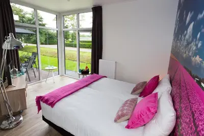 a bedroom with a large bed with pink sheets and pillows at EuroParcs Buitenhuizen in Velsen-Zuid