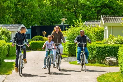 three people riding bikes down a path in a yard at EuroParcs Molengroet in Noord-Scharwoude
