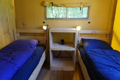 two beds in a small room with a window at EuroParcs Molengroet in Noord-Scharwoude