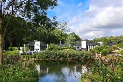 a house with a river in the foreground at EuroParcs Spaarnwoude in Halfweg