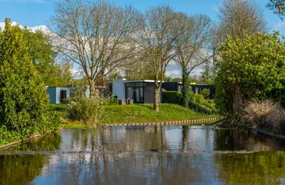 a view of a house from the river at EuroParcs Spaarnwoude in Halfweg