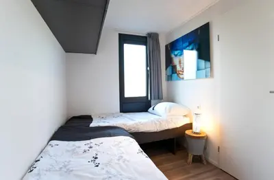 two beds in a small room with a window at EuroParcs Spaarnwoude in Halfweg