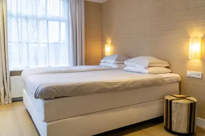 a bedroom with a large white bed with a window at Boerderie De Gouden Leeuw in Voorschoten
