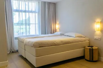a large bed in a room with a window at Boerderie De Gouden Leeuw in Voorschoten