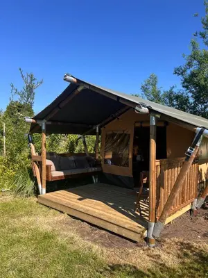 a gazebo with a black roof and a wooden deck at Een luxe safari tent in Rijsenhout
