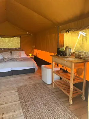 a bedroom with a bed and a desk in a tent at Een luxe safari tent in Rijsenhout