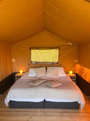a bed in a tent with two towels on it at Een luxe safari tent in Rijsenhout