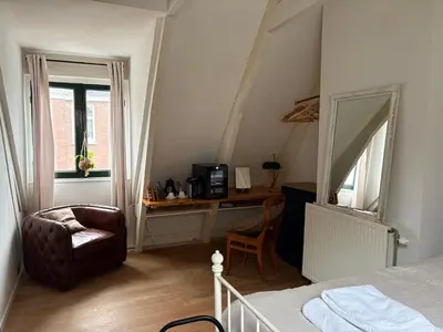 a bedroom with a bed and a chair and a mirror at Bellamy Suites in Amsterdam