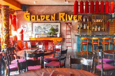a restaurant with tables and chairs and a golden river sign at De Groene Afslag Hotel in Bussum