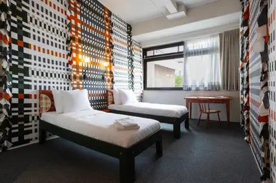a room with two beds and a table and a window at De Groene Afslag Hotel in Bussum