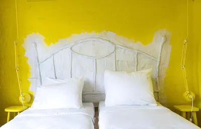 two beds with white pillows and a yellow wall at De Groene Afslag Hotel in Bussum