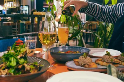 a table with food and a person pouring a glass of wine at De Groene Afslag Hotel in Bussum