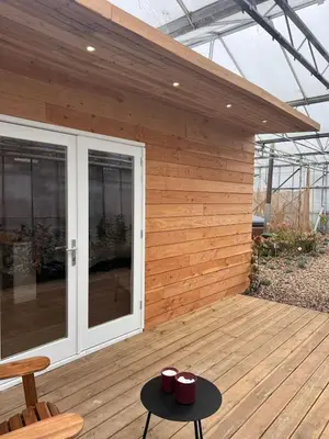 a wooden deck with two red cups on a table at Luxurious Tiny House with HotTub in Rijsenhout