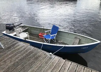 a blue boat with a chair sitting on a dock at Luxurious Tiny House with HotTub in Rijsenhout