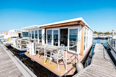 a small boat with a table and chairs on a dock at Floating Holiday Home - 15 mins to AMS in Vinkeveen