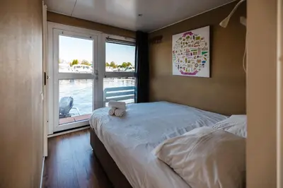 a bedroom with a bed and a large window at Floating Holiday Home - 15 mins to AMS in Vinkeveen