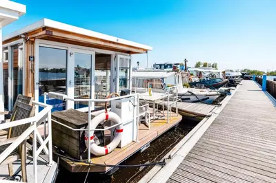 a small boat docked at a dock with other boats at Floating Holiday Home - 15 mins to AMS in Vinkeveen